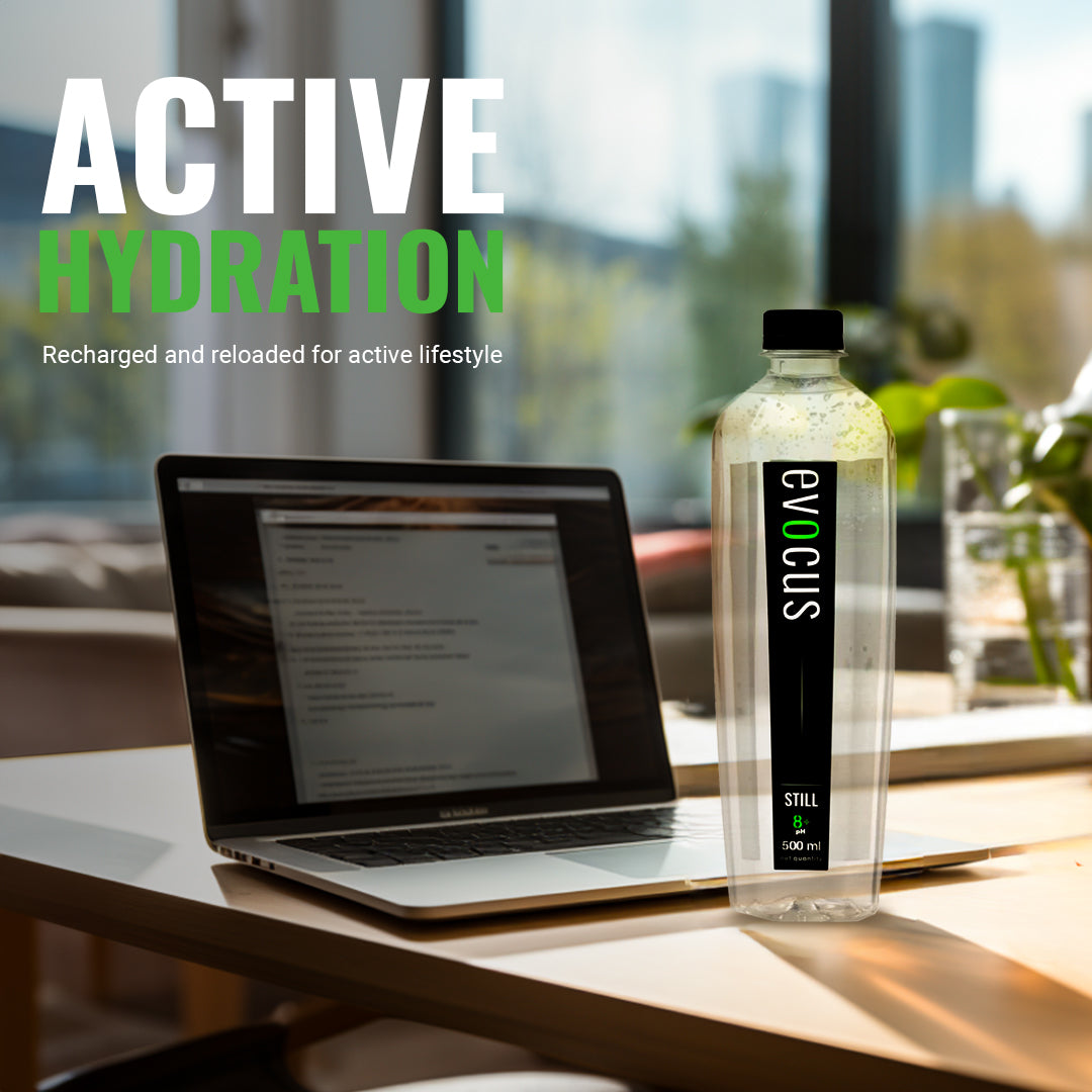 A clear bottle of Evocus Still Alkaline Water sits on a desk beside a laptop. Text emphasizes its role in "Active Hydration" for an active lifestyle.