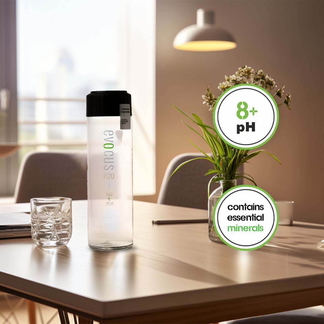 A Glass bottle of Evocus Still Alkaline Water sits on a table with text emphasizing its 8+ pH and essential mineral content.