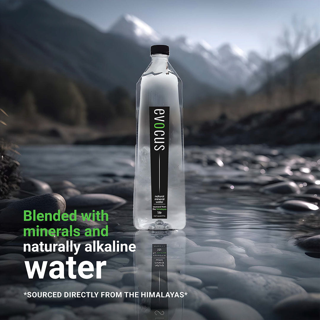 A clear bottle of Evocus Natural Mineral Water sits on rocks by a river. Text emphasizes its Himalayan source and alkaline properties.