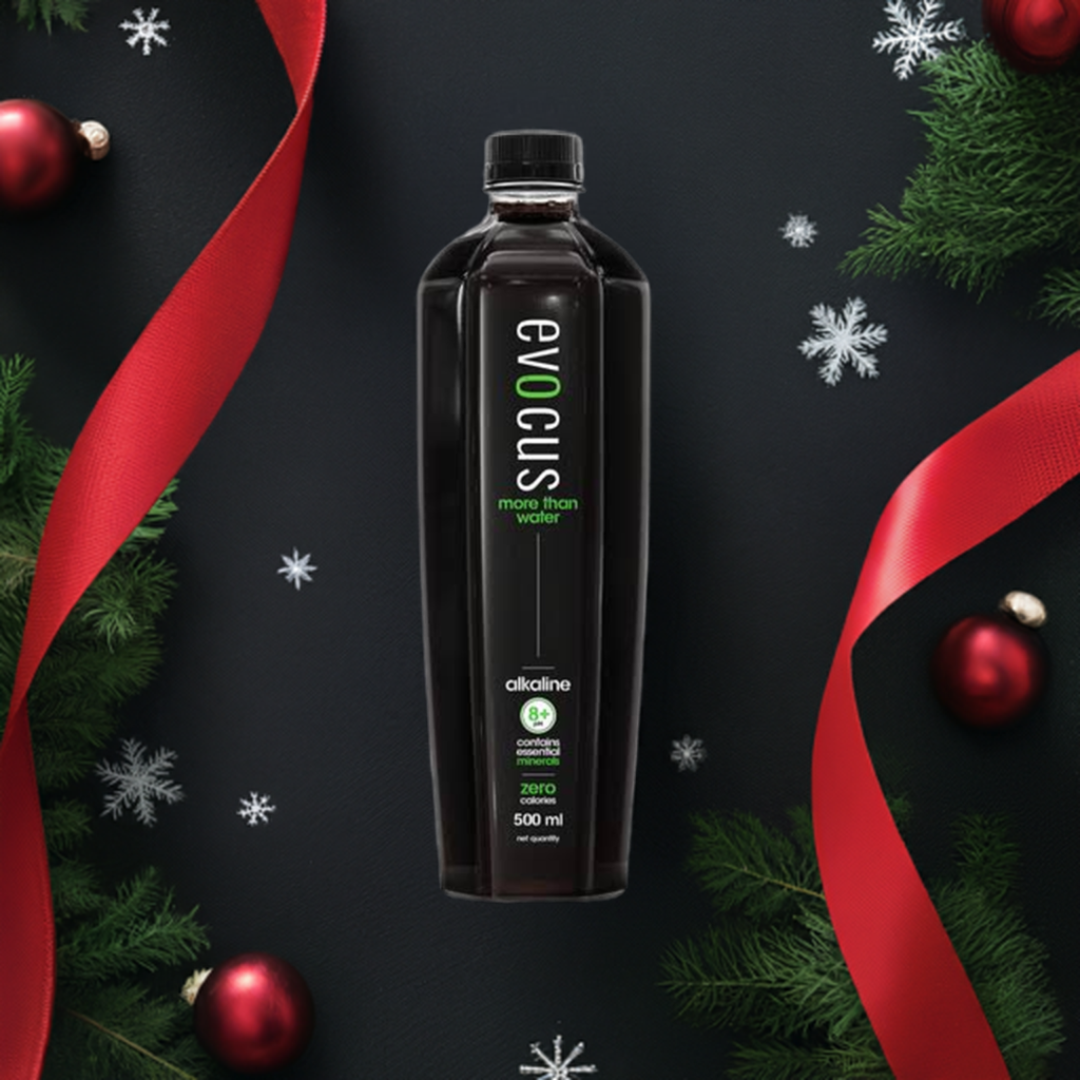 A bottle of Evocus black alkaline water rests amidst festive Christmas decorations.