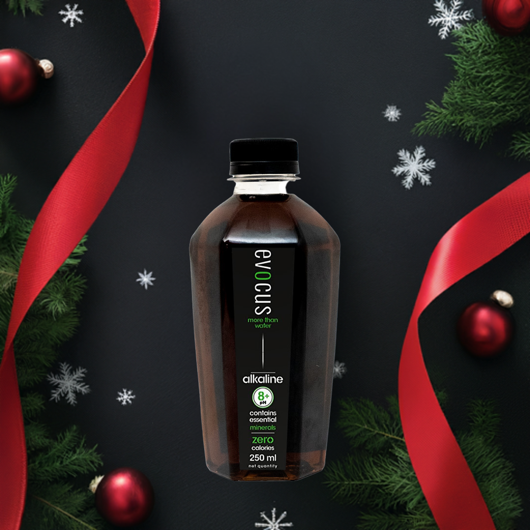 A bottle of Evocus black alkaline water rests amidst festive Christmas decorations.